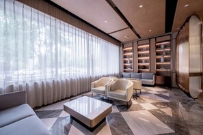 A modern living room with a sofa, armchairs, a coffee table, and a bookshelf with decorative items.