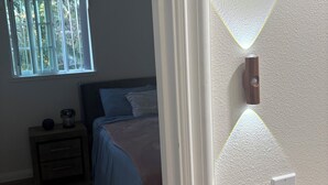 Une chambre à coucher avec un lit, une table de chevet, une fenêtre et un ventilateur de plafond.