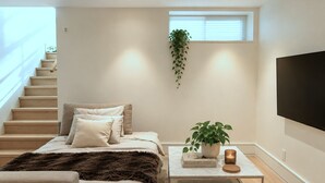 Ein modernes Schlafzimmer mit einem Bett, einem Couchtisch mit Pflanze, einem Fernseher und einer Treppe.