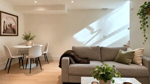 Ein modernes Wohnzimmer mit einer Couch, einem Couchtisch, einem Essbereich mit Stühlen und einer hängenden Pflanze.