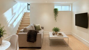Ein modernes Wohnzimmer mit Sofa, Couchtisch und Fernseher.