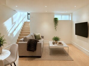 Ein modernes Wohnzimmer mit Sofa, Couchtisch und Fernseher.