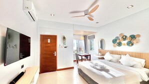 Una habitación de hotel moderna con cama, escritorio, televisor, ventilador de techo y un adorno en la pared.