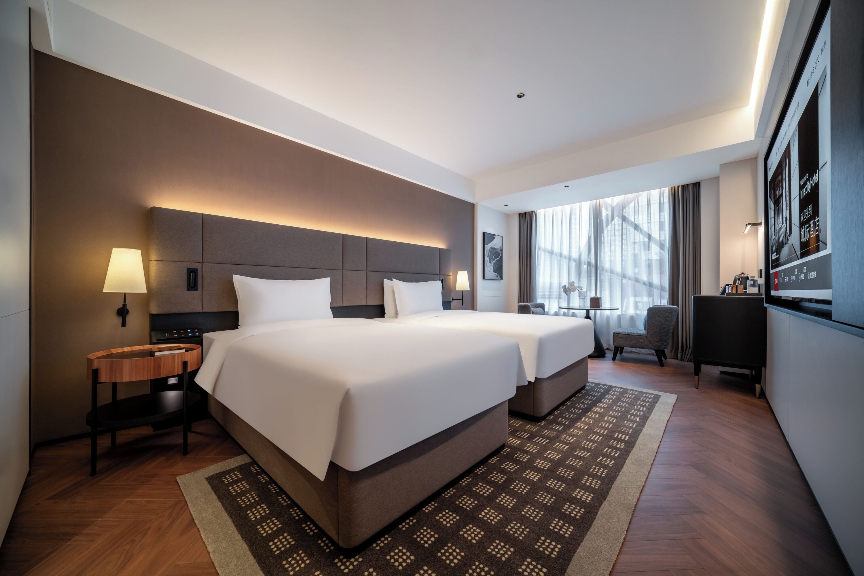 A hotel room with a large bed, bedside tables, a desk, and a chair.