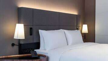 A hotel room with a large bed, two bedside lamps, a bedside phone, and a wooden side table.