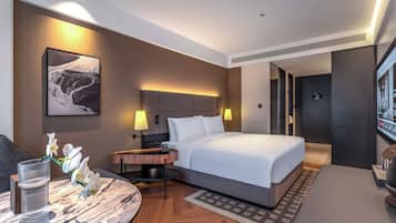 Una habitación de hotel moderna con una cama grande, mesitas de noche, un escritorio y un televisor.
