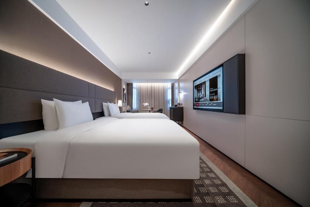 Une chambre d’hôtel avec un grand lit, un téléviseur fixé au mur et un bureau avec une chaise.