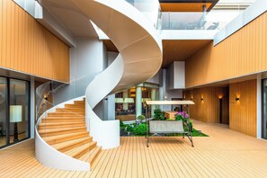 Et moderne interiør med en spiralopsats, trægulv og et siddeområde med planter.