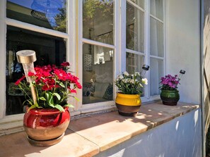 Un rebord de fenêtre orné de trois pots de fleurs, chacun ayant un pot et des fleurs de couleur différente.