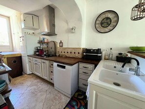 A compact kitchen with white cabinets, a dishwasher, a stove, and a sink. - House for 4 people with private access to the beach - Giens (HYERES)