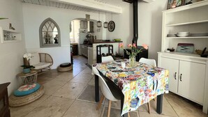 Una cocina con gabinetes blancos, una mesa de comedor con mantel colorido y una estufa negra.