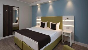 Ett modernt hotellrum med en stor säng, sängbord, en spegel och en garderob.
