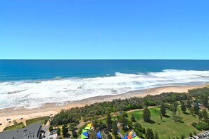A coastal view with a beach, ocean waves, and a park area with trees and a building. - Mega Ocean View Skyhome at Oracle Level 37 (Gold Coast)