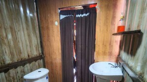 A small, compact bathroom with a toilet, sink, and shower area.