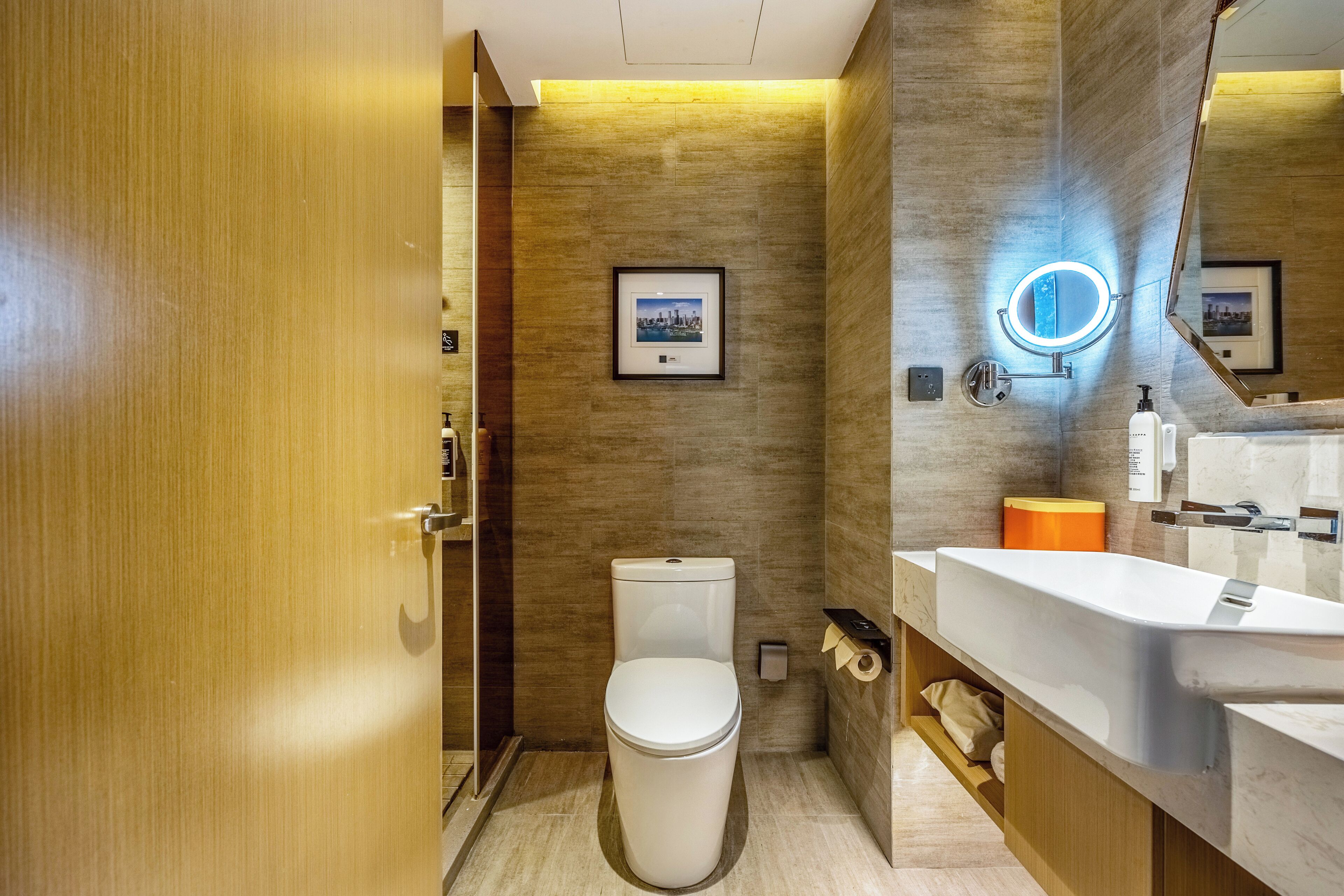 Un baño moderno con inodoro, lavamanos y espejo.