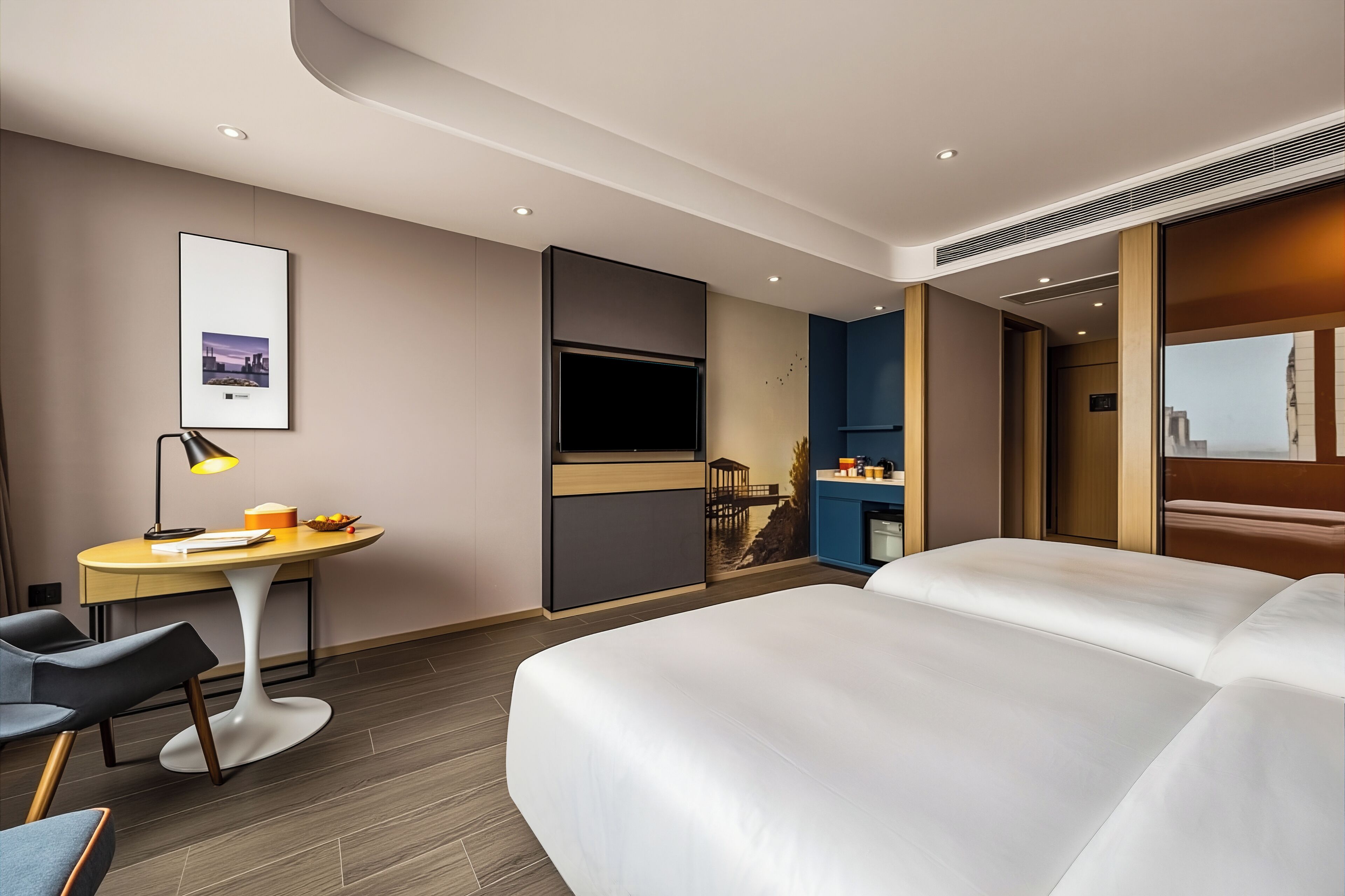 Camera d'albergo moderna con un letto grande, una scrivania con lampada, una televisione e vista sulla città.