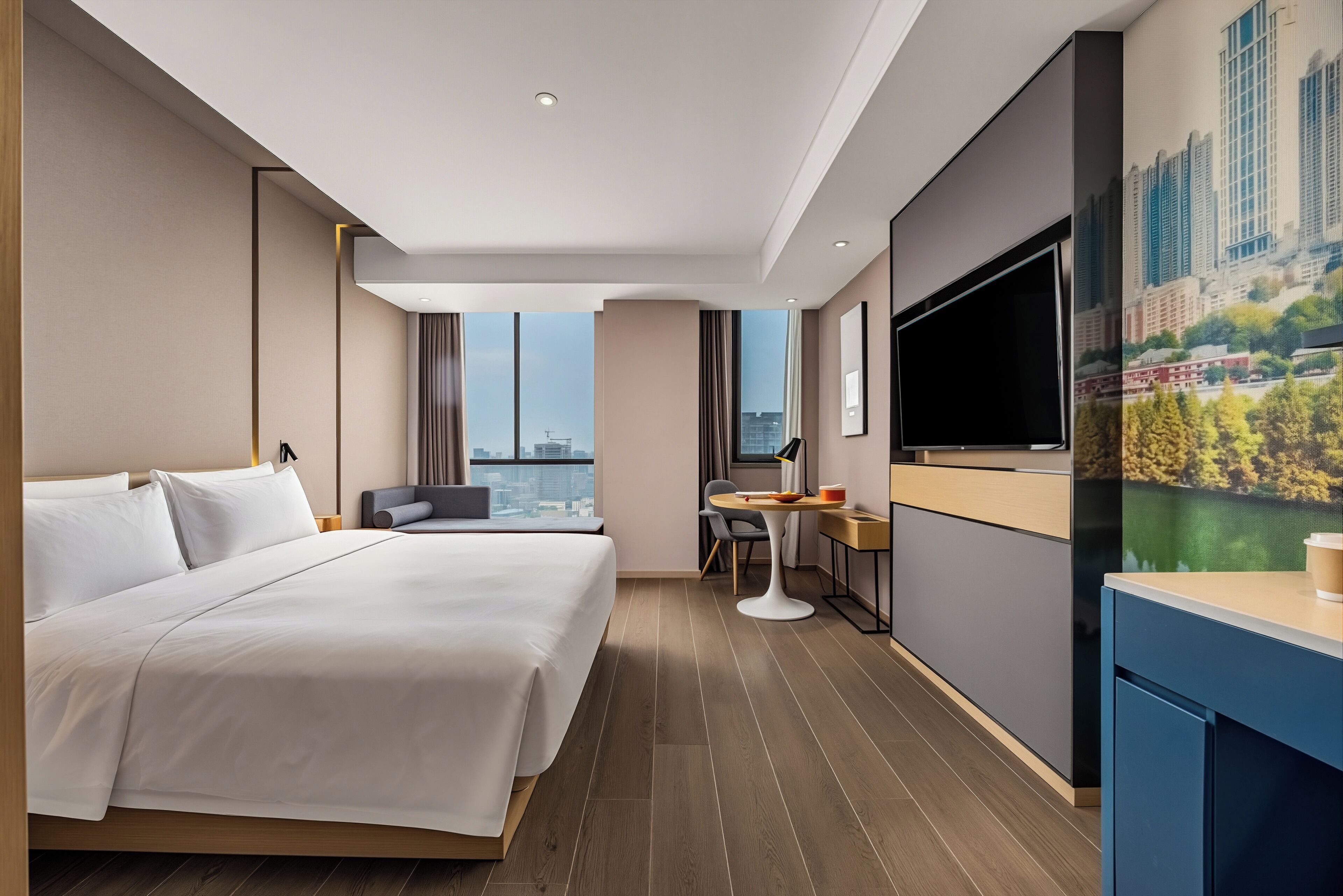A modern hotel room with a large bed, a desk, a chair, a flat-screen TV, and a cityscape view.