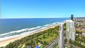 Un paisaje urbano costero con una playa, edificios altos y un cielo azul despejado.