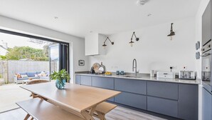 Una cocina moderna con una mesa y banco de madera, armarios grises e iluminación colgante.