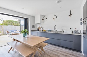 Eine moderne Küche mit Holztisch und Bank, grauen Schränken und Pendelleuchten.