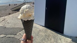 Un cono de helado en la playa frente a un edificio que dice 'FISHERMAN'S HUT'.