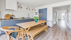 Una cocina moderna con una mesa y sillas de madera, una estufa y un lavamanos.