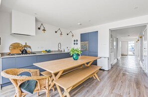 Eine moderne Küche mit einem Holztisch und Stühlen, einem Herd und einem Spülbecken.