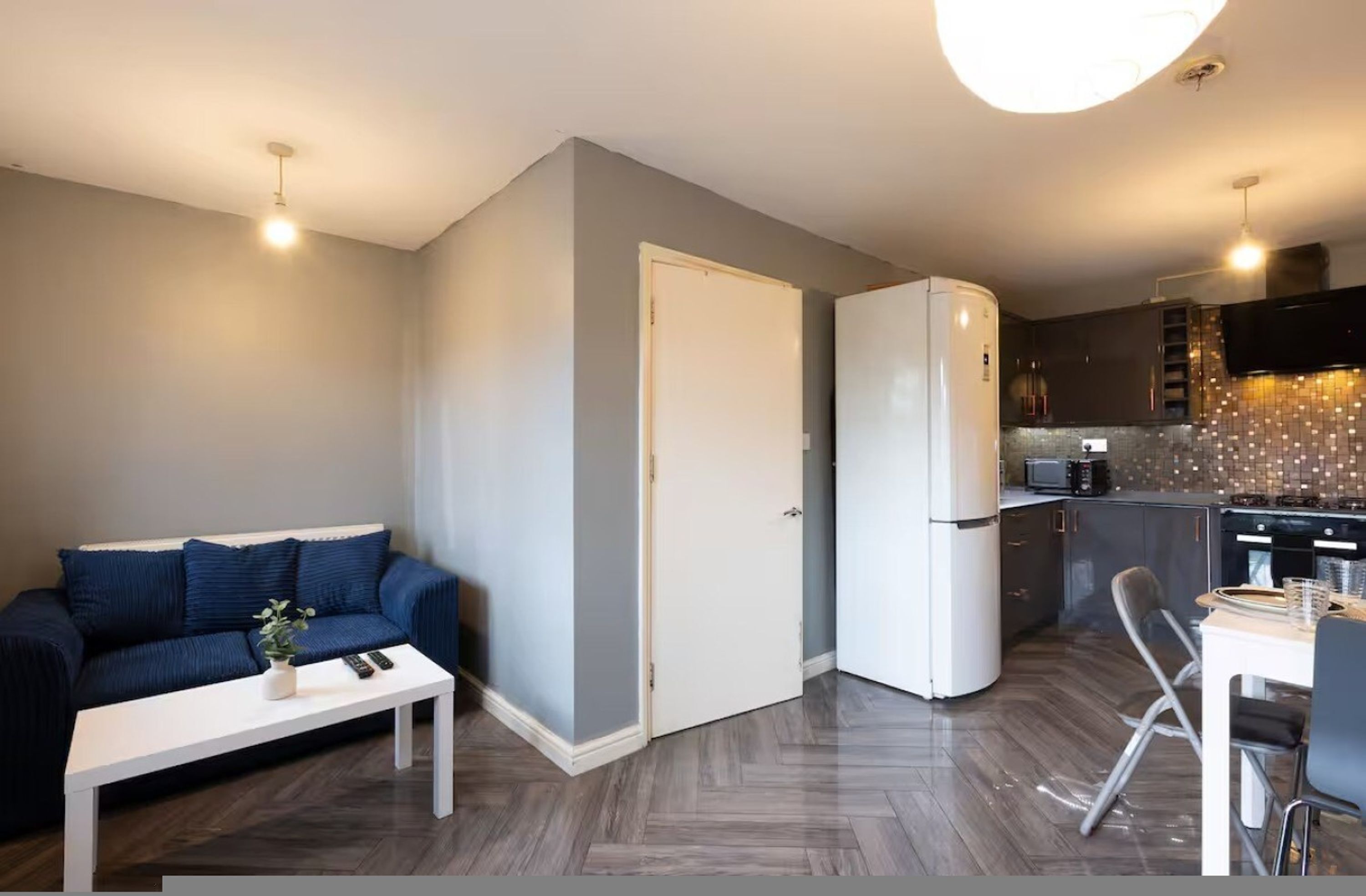 A modern apartment with a living room, kitchenette, and a dining area.