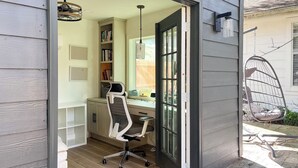 Ein Homeoffice mit Schreibtisch, Stuhl, Bücherregal und einem Hängesessel im Freien.