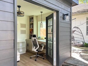 A home office with a desk, chair, bookshelf, and a hanging chair outside.