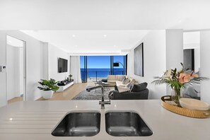 Eine moderne Küche mit einer großen Kochinsel, ein Essbereich mit Aussicht und ein Wohnzimmer mit Sofa und Couchtisch.