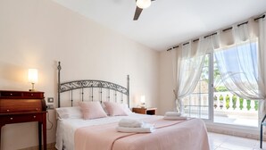 Ein Schlafzimmer mit Bett, Nachttischen, einem Schreibtisch und einem Fenster mit Vorhängen.