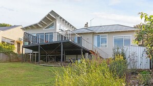 A residential property with a covered outdoor area, a sloped roof, and a fenced yard.