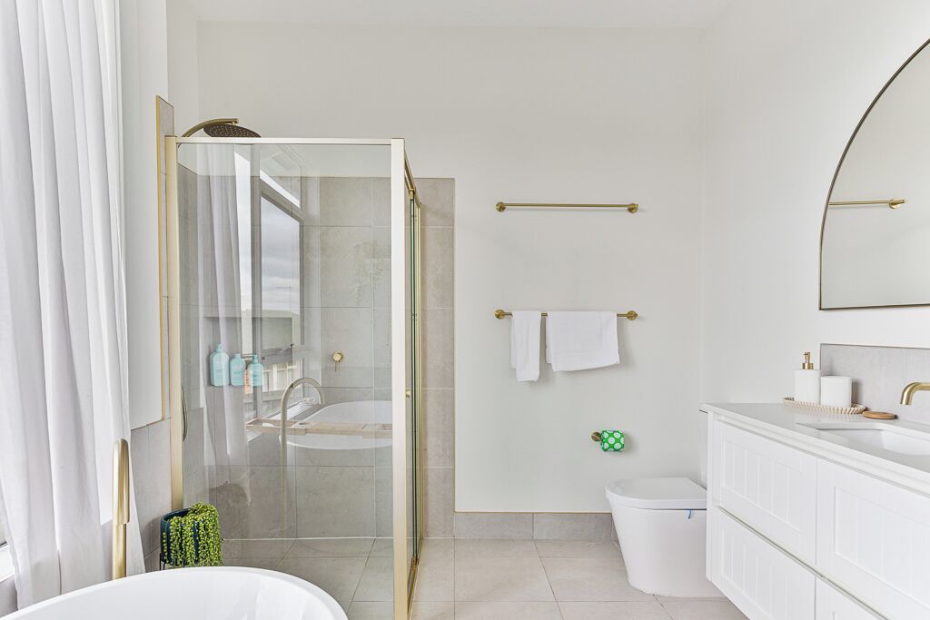 Une salle de bain moderne avec une douche à parois de verre, une baignoire et un meuble-lavabo blanc avec un miroir.