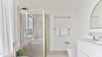 Une salle de bain moderne avec une douche à parois de verre, une baignoire et un meuble-lavabo blanc avec un miroir.