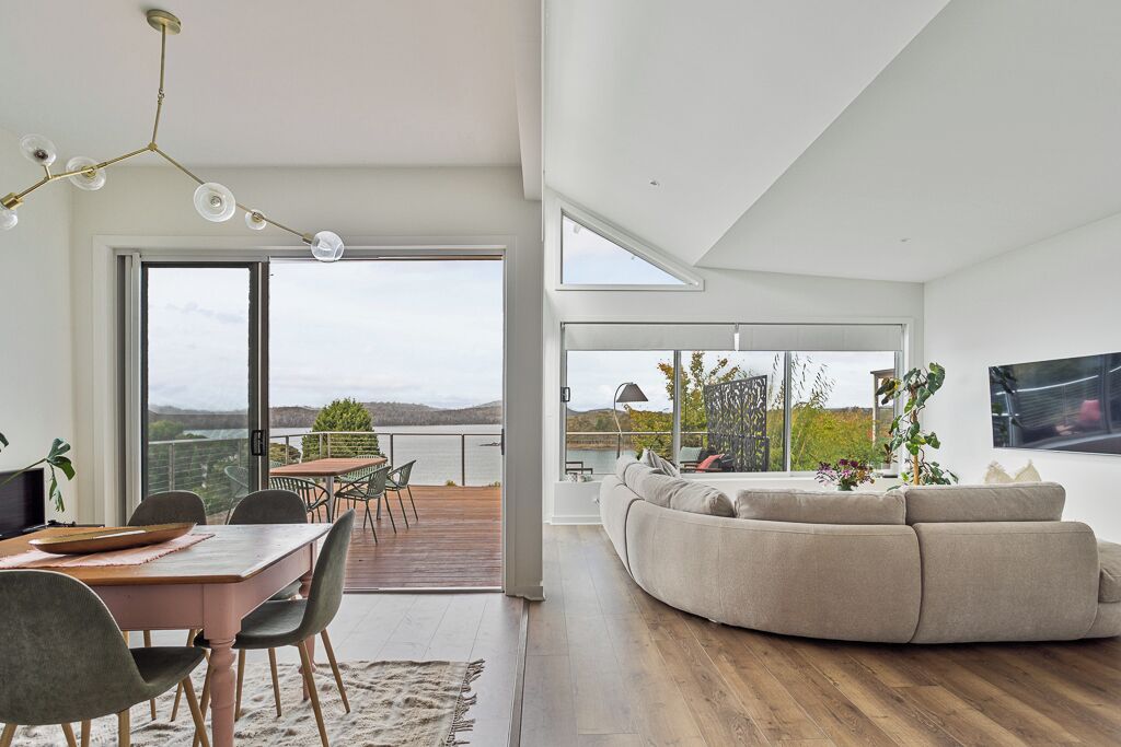 A modern living room with a large sofa, a dining area with a table and chairs, and a view of the outdoors.