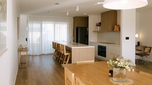 A modern kitchen with wooden cabinets, a central island, and a dining area with a wooden table and chairs. - Welcome to 'Good Vibes' - town central and yes it lives up to it's name. (Robe)