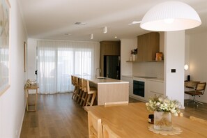 Eine moderne Küche mit Holzschränken, einer zentralen Kochinsel und einem Essbereich mit Holztisch und Stühlen.