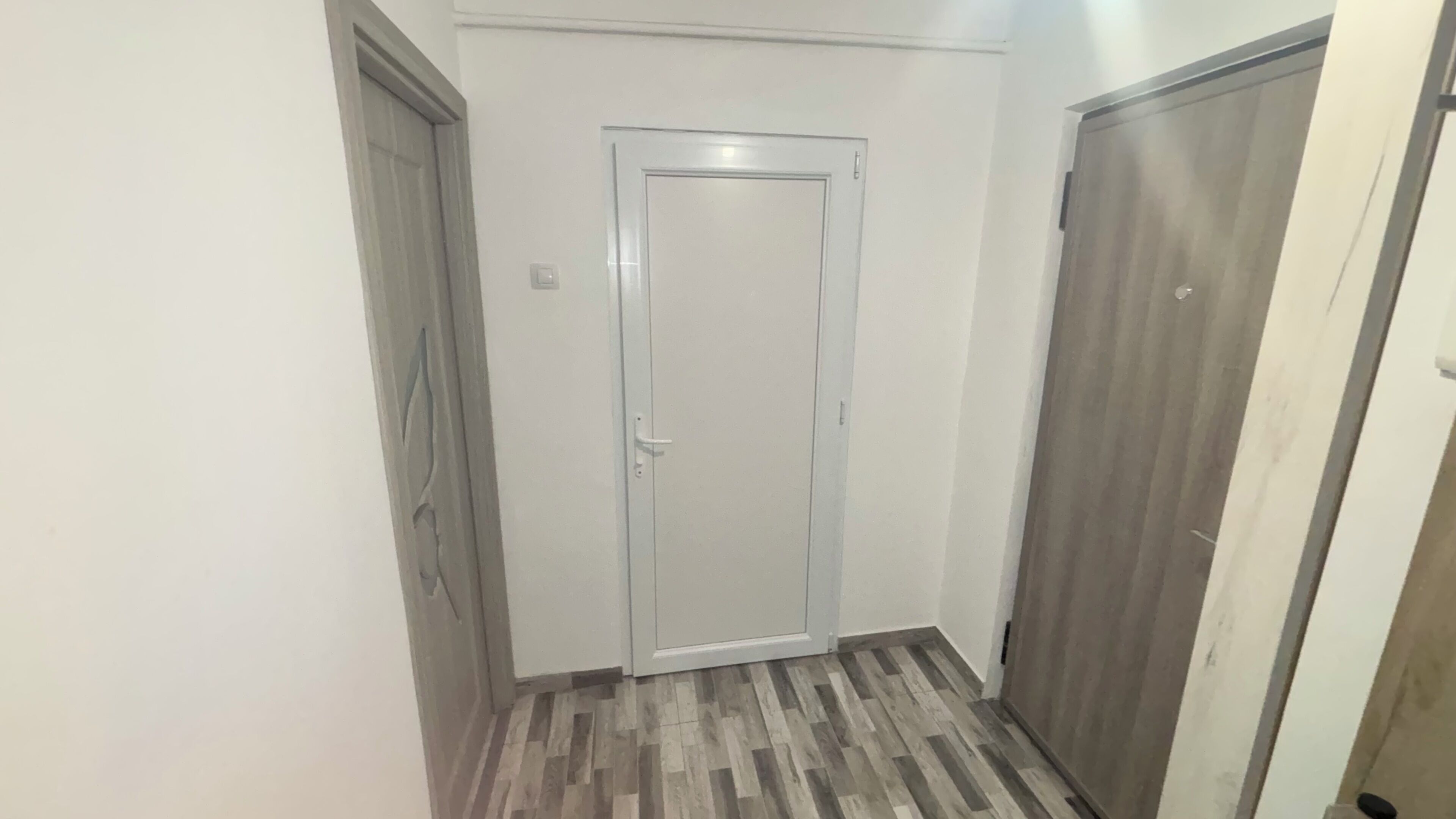 Ein Flur mit einer Holztür, einer weißen Tür und einem Holztürrahmen.