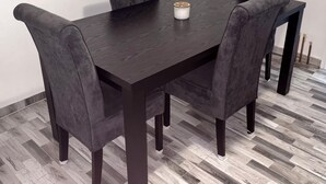 A rectangular dining table with four dark chairs, a white object on the table, and a herringbone-patterned floor. -  Home Away From Home: Bright Quiet Fully Equipped Self Check-In Central Location (Râmnicu Vâlcea)