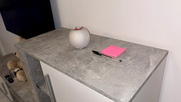 A grey stone table with a silver textured vase, a pink sticky note, and a black pen.