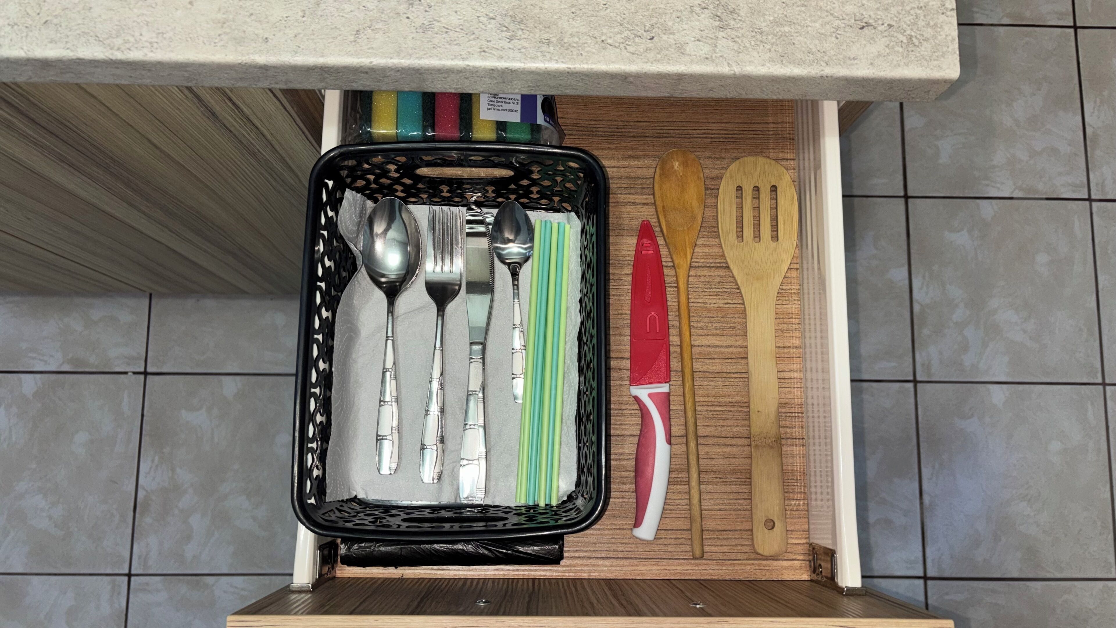 Un cajón de cocina con utensilios y una tabla de cortar.