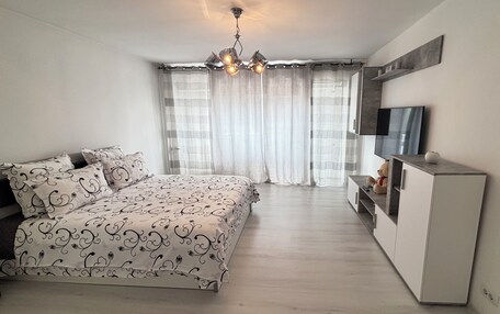 A bedroom with a bed, curtains, a TV, and a desk.