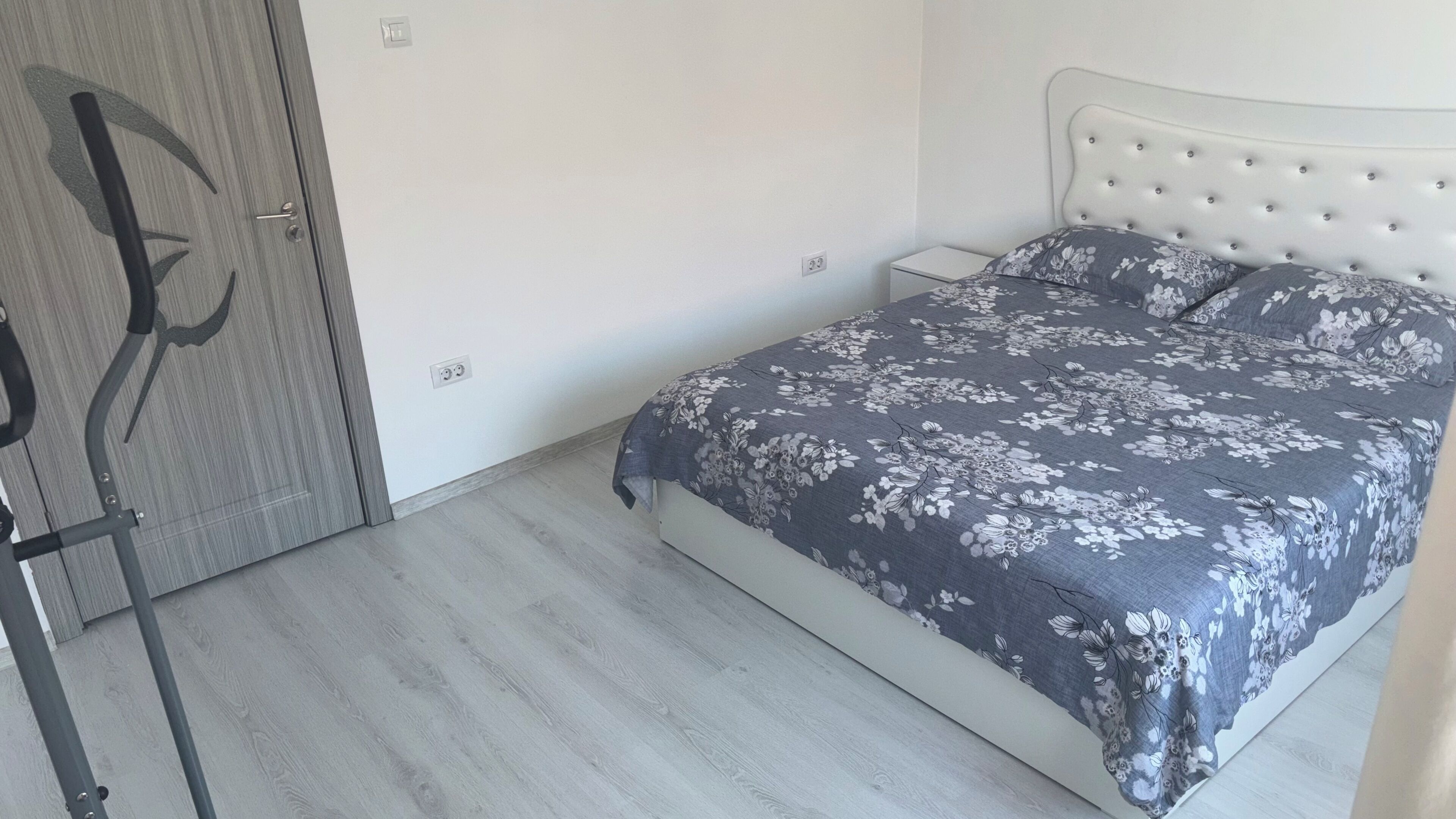 A bedroom with a bed, a nightstand, a wardrobe, and a door.
