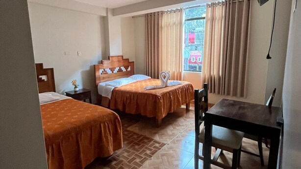 Habitación de hotel con dos camas, una mesa de comedor y una lámpara en el techo.