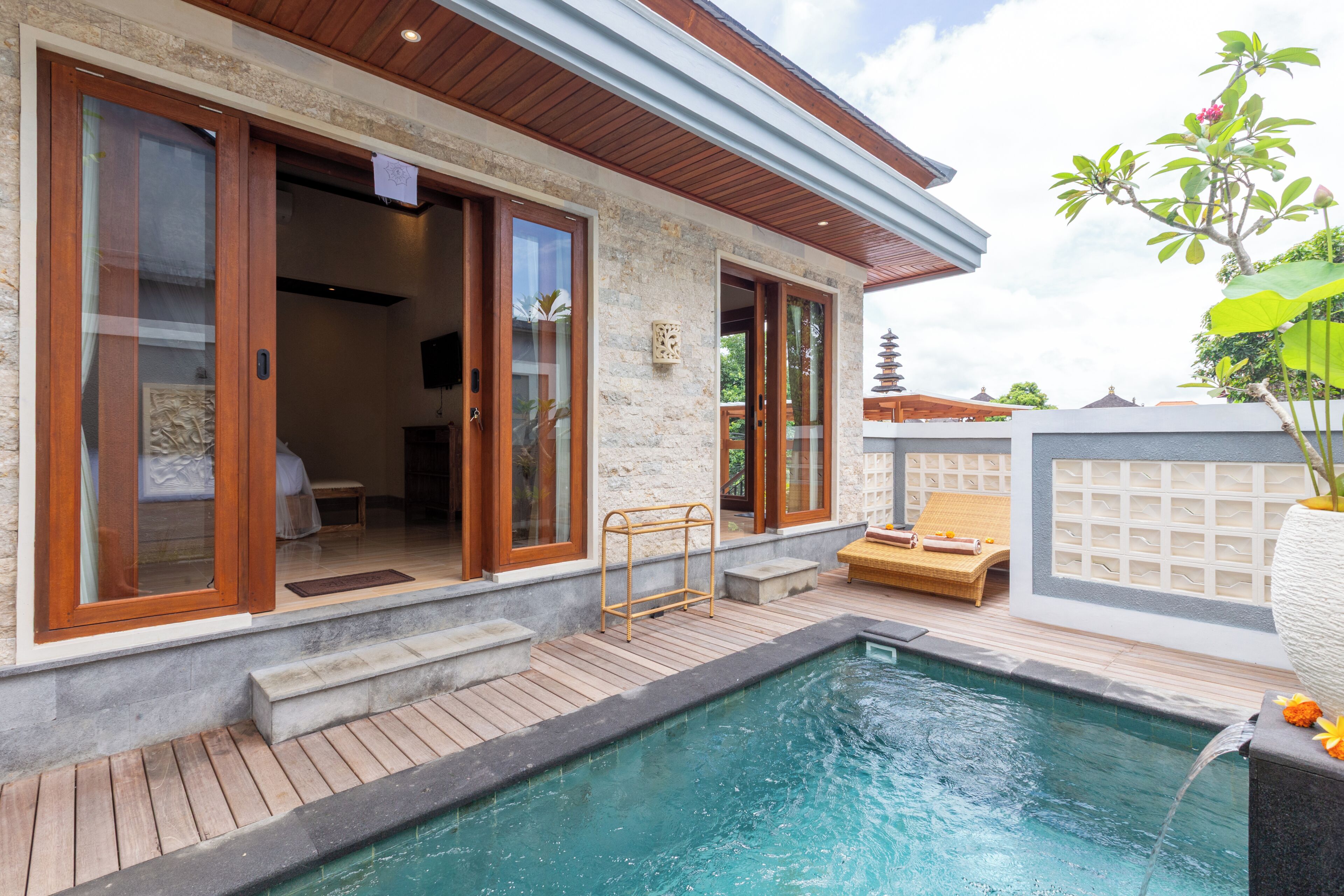 A modern building with a swimming pool, wooden deck, and a traditional pagoda in the background.