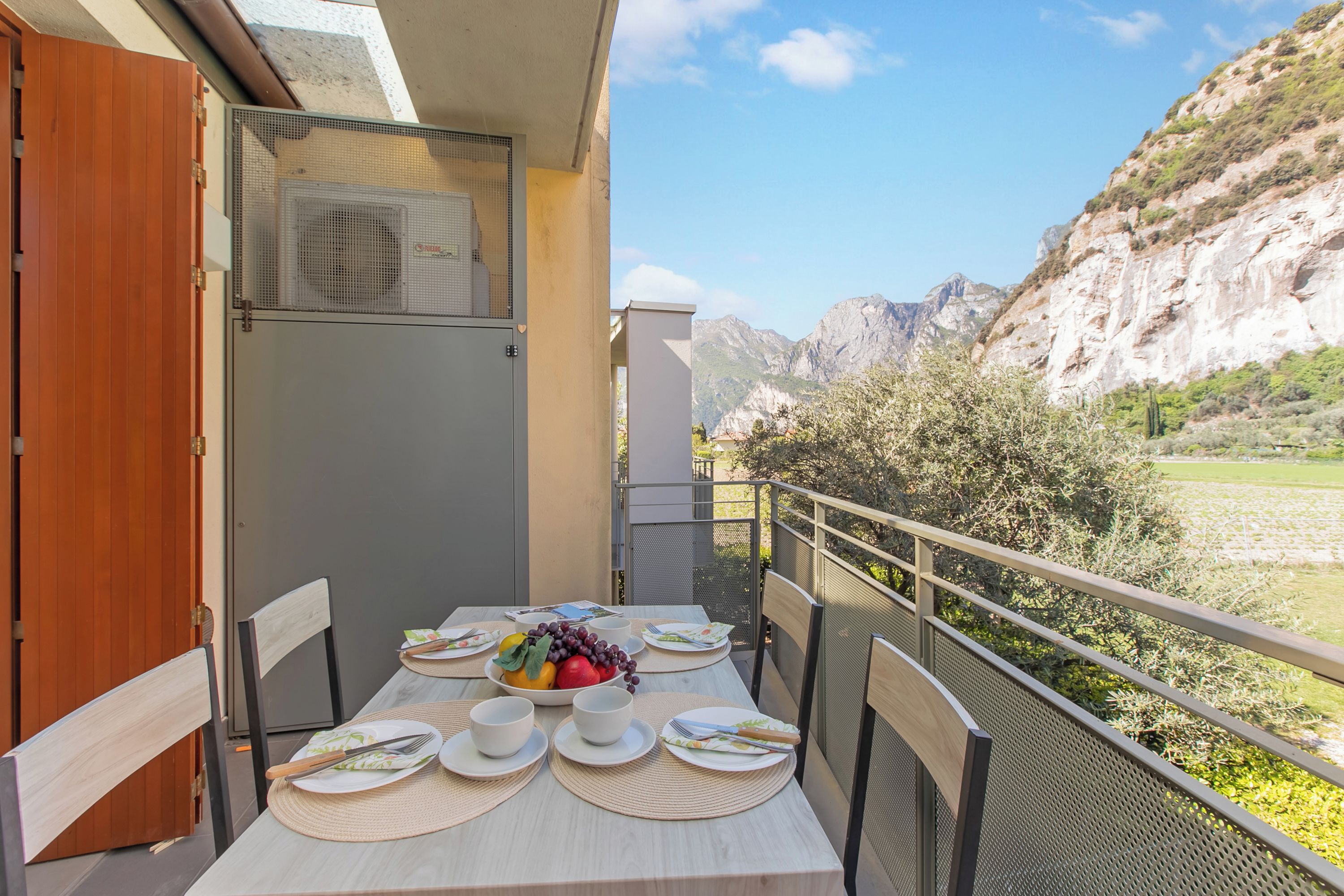 A balcony with a table set for dining, overlooking a mountainous landscape.