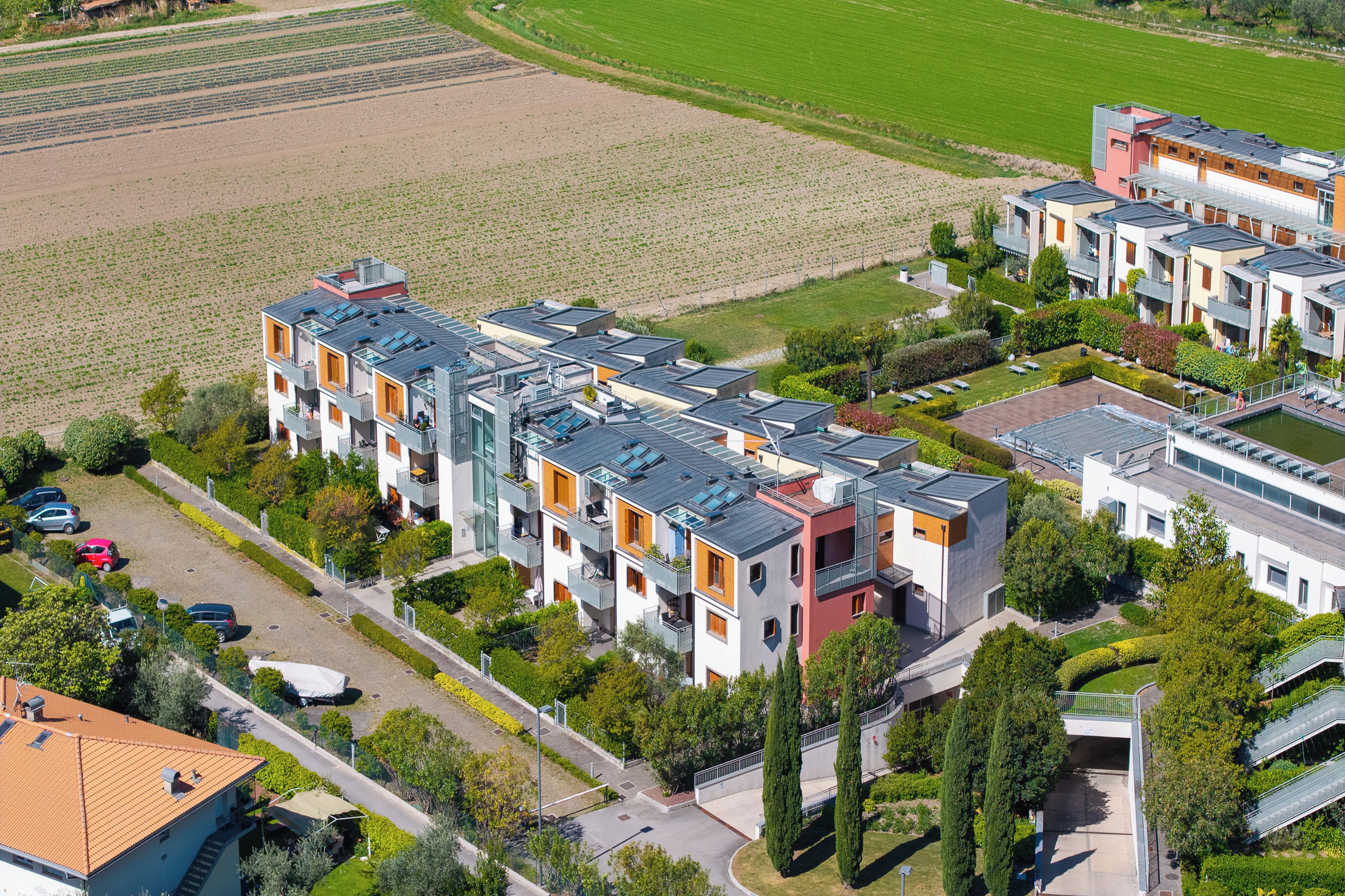 Un moderno complejo residencial con varios edificios de apartamentos, un patio central y zonas verdes circundantes.
