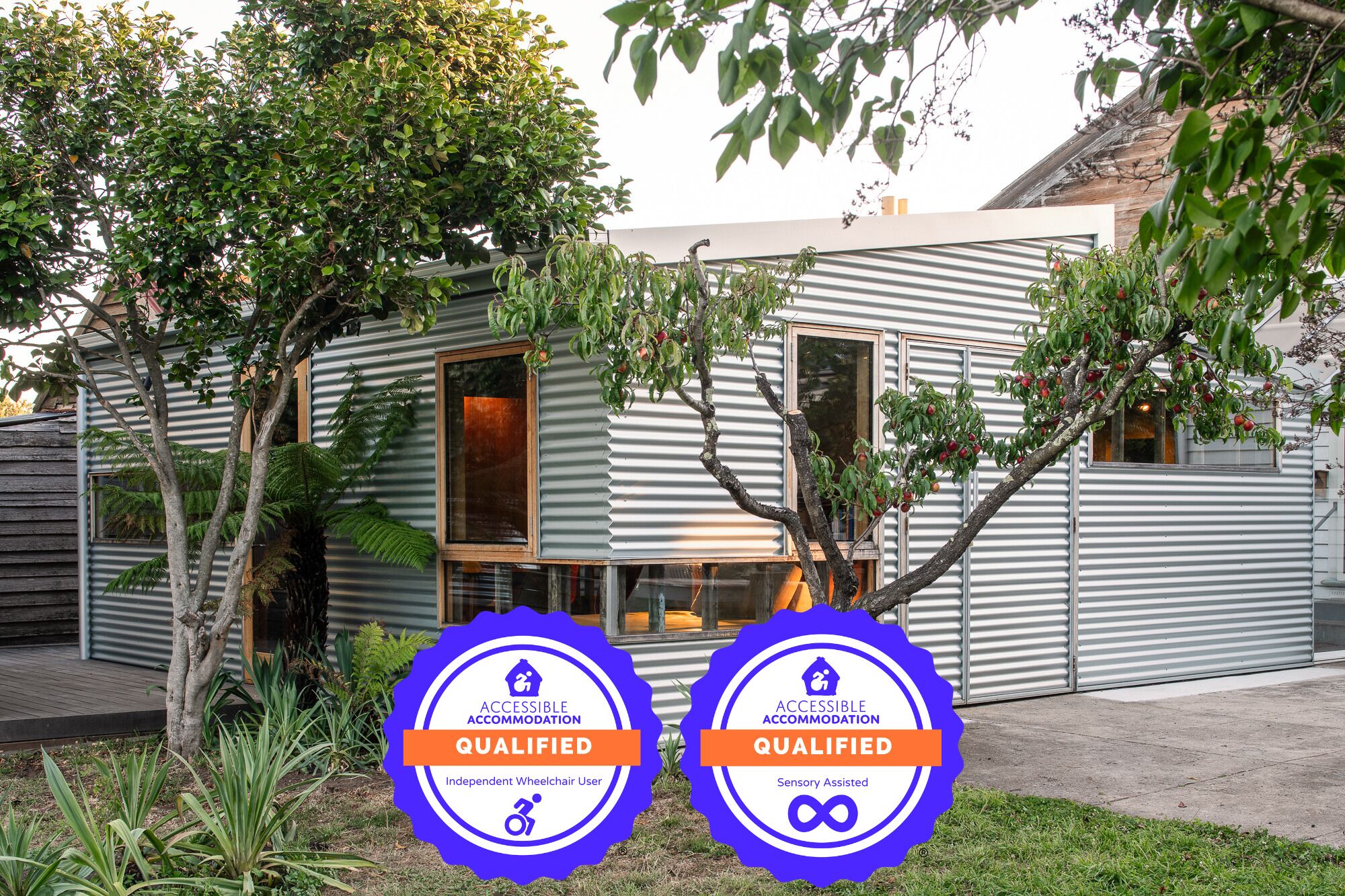 A modern building with two accessible accommodation badges indicating it is wheelchair accessible and sensory assisted.