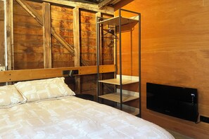 A bedroom with a bed, a wooden wall, a metal shelf unit, and a television.